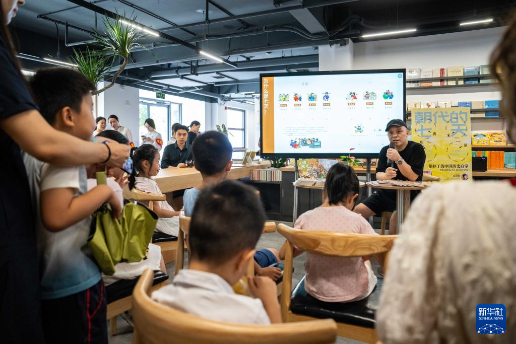 6月28日,在长沙图书馆湘江新区周家湾分馆,志愿者为小朋友进行书籍导读。