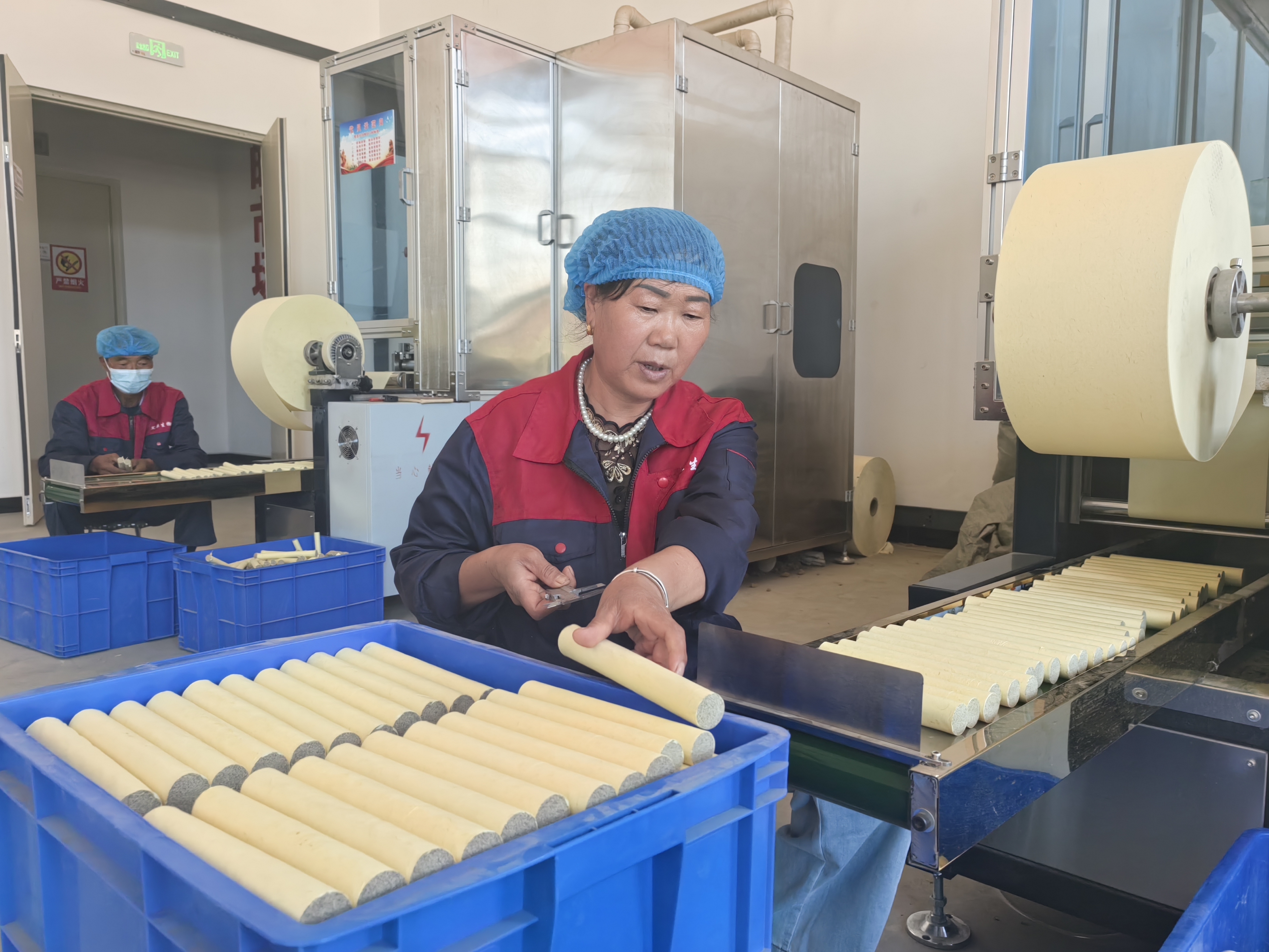 村民马雪琴在艾草加工车间卷制艾条