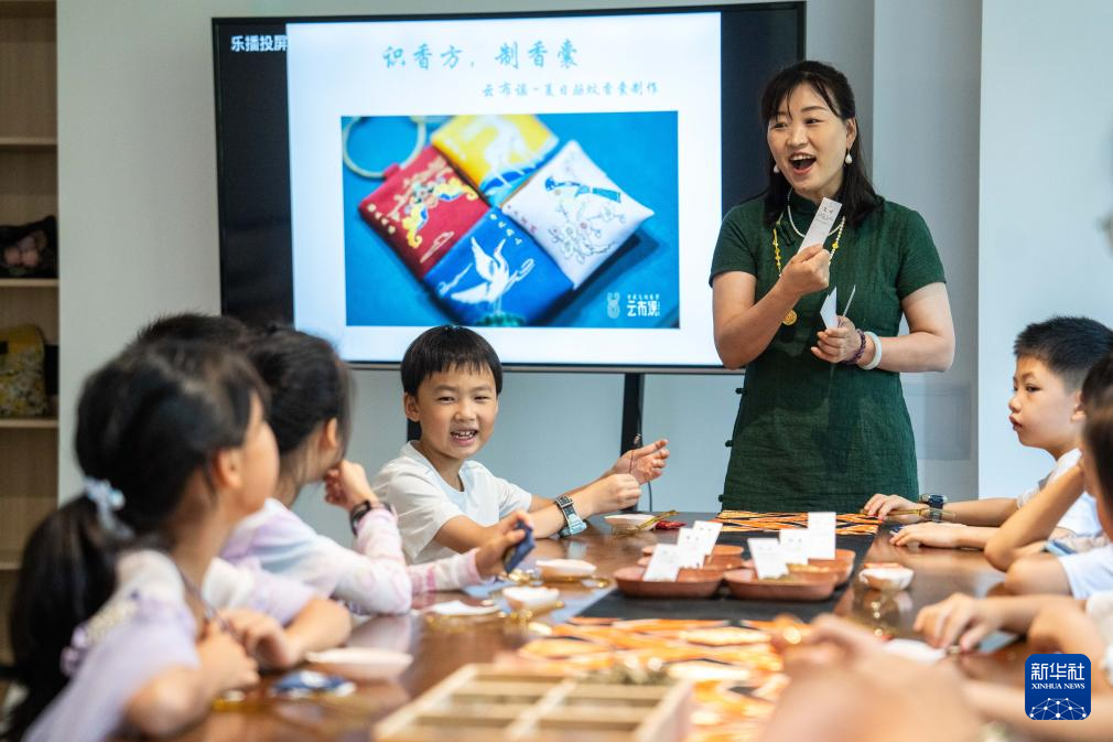 6月28日,在长沙图书馆湘江新区周家湾分馆,志愿者指导小朋友制作香囊。