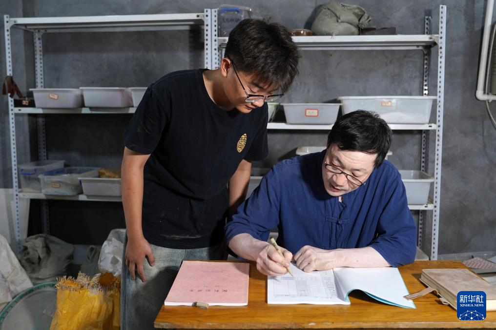 6月28日，张志忠（右）和学生研究记录烧制白瓷的原料配方。