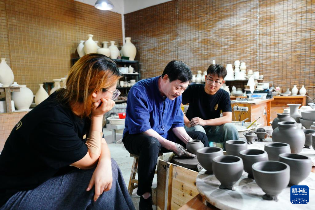 6月28日，张志忠（中）在给学生讲解瓷器制作技巧。