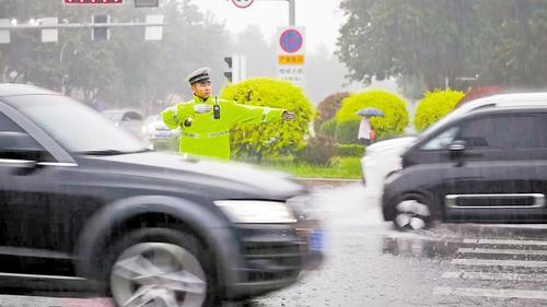 7月2日，在保定市莲池区七一路与恒祥大街交口，交警冒雨疏导交通。 本报记者 许佳奇摄
