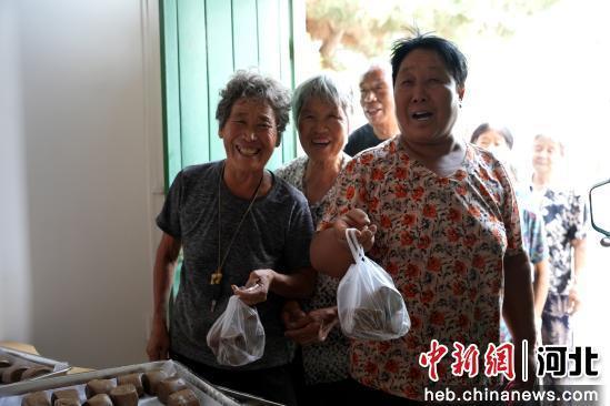 图为7月10日，河北省隆尧县山口镇北潘庄村村委会敬老食堂，老人们在领取馒头。 张冬茹 摄