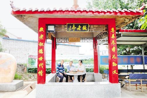 7月2日，在圪塔坨村敬老亭，“老帮老”志愿服务队成员翻看志愿服务资料。 本报记者 王育民摄