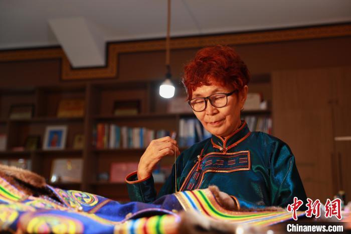 图为娜仁其其格正在手工缝制传统蒙古族服饰 陈坤 摄