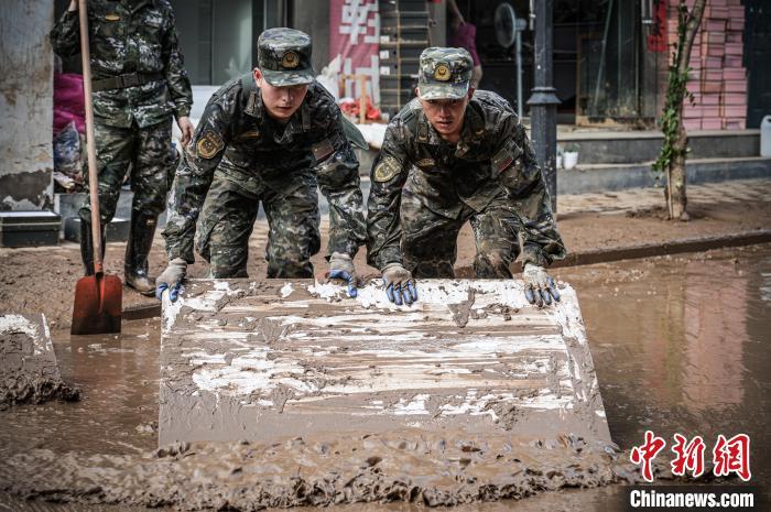 图为武警商洛支队官兵合力清理道路杂物，恢复交通秩序。 徐宝帅 摄