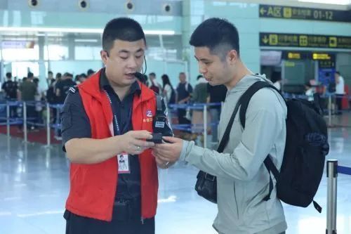 ▲ 南昌昌北国际机场工作人员为旅客检查充电宝是否合规。