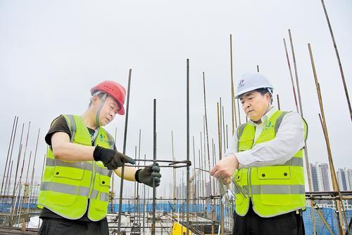 6月19日，在沧州市通泰园项目现场，白晓军（右）为工人讲解钢筋绑扎注意事项。 本报记者 王雅楠摄