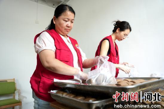 图为7月10日，河北省隆尧县山口镇北潘庄村村委会敬老食堂，志愿者在分装馒头。 张冬茹 摄