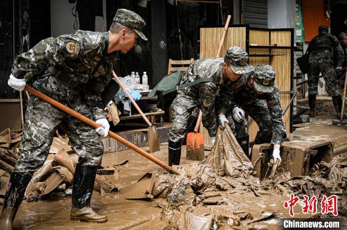 图为武警官兵利用木板，排除险情，向道路两侧推赶洪水。 徐宝帅 摄