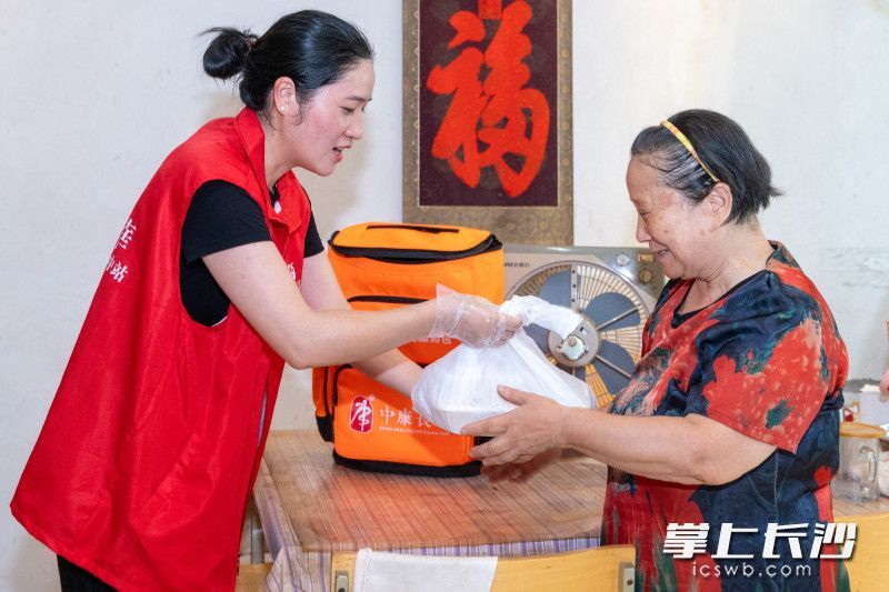 习萍（左）将饭菜送到黄福秋老人家中。