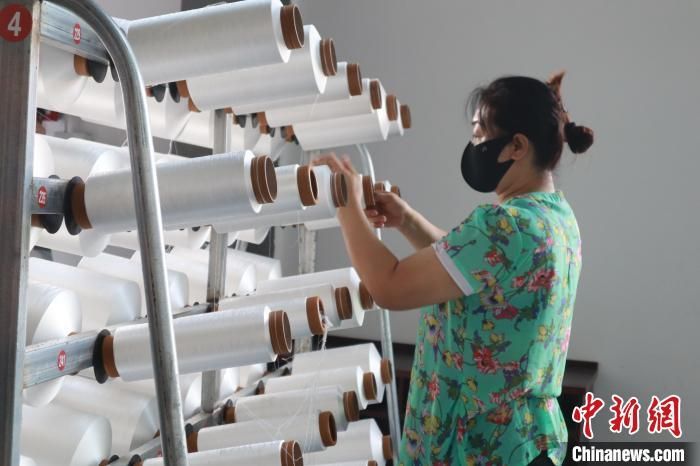 7月11日，汉阴县智能化高端纱线纺织项目现场，工作人员检查产品。　李一璠 摄