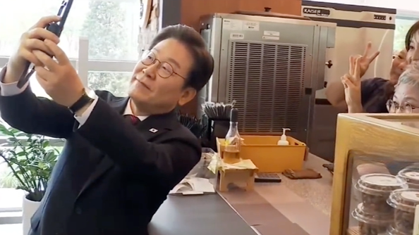 李在明在食堂与学员共进午餐，为女学员拉椅子，与食堂员工自拍合影