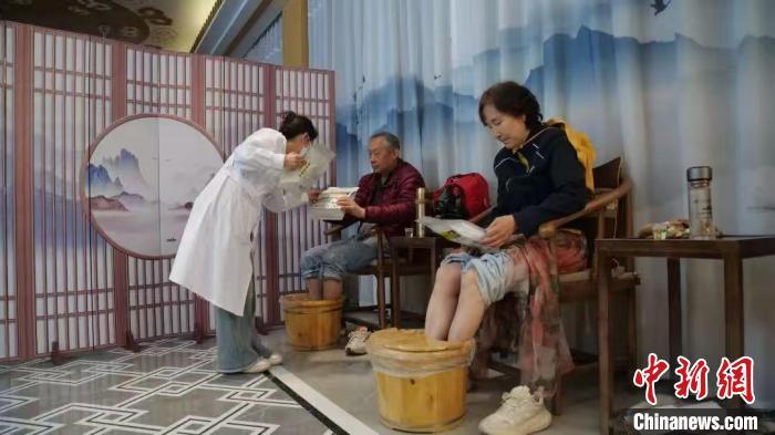 2025年“五一”假期，宕昌县康养驿站内，工作人员为体验中药足浴的游客介绍当地中药茶饮。闫姣　摄
