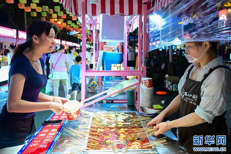 7月10日，游客在洛阳市西工小街选购美食。