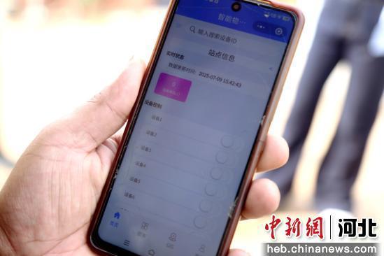 图为村民正在操作手机打开伸缩式喷灌设备。 郭江鹏 摄