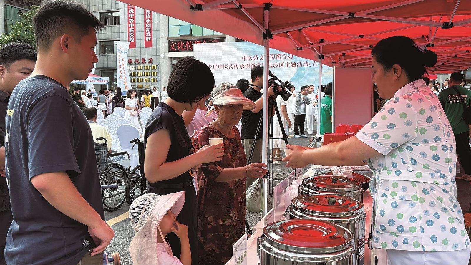中医药文化夜市的“药食同源”品鉴区里，人参鸡汤蒸腾着热气，酸梅汤、绿豆饮温热解暑，市民纷纷品尝。