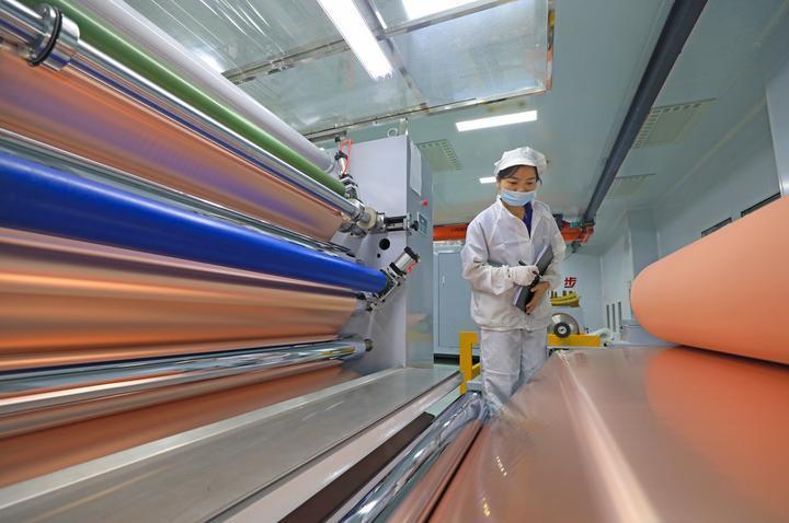 江西省丰城市循环经济产业园江西麦得豪新材料有限公司员工在新投产的生产线上查看超薄电子级铜箔质量情况。