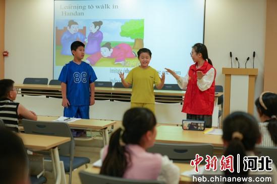 图为青年志愿者正在带领社区小朋友排练英文版成语情景剧《邯郸学步》。 王倩倩 摄