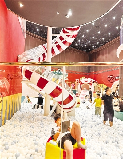 家長帶著孩子在南昌萬象城一兒童樂園內玩耍