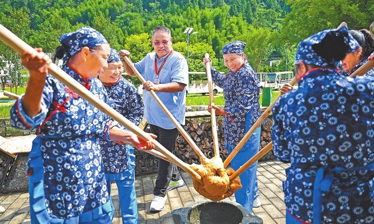 7月17日,在上犹县梅水乡园村村,外媒嘉宾体验黄元米果的制作工艺。江西日报全媒体记者 张翰林摄