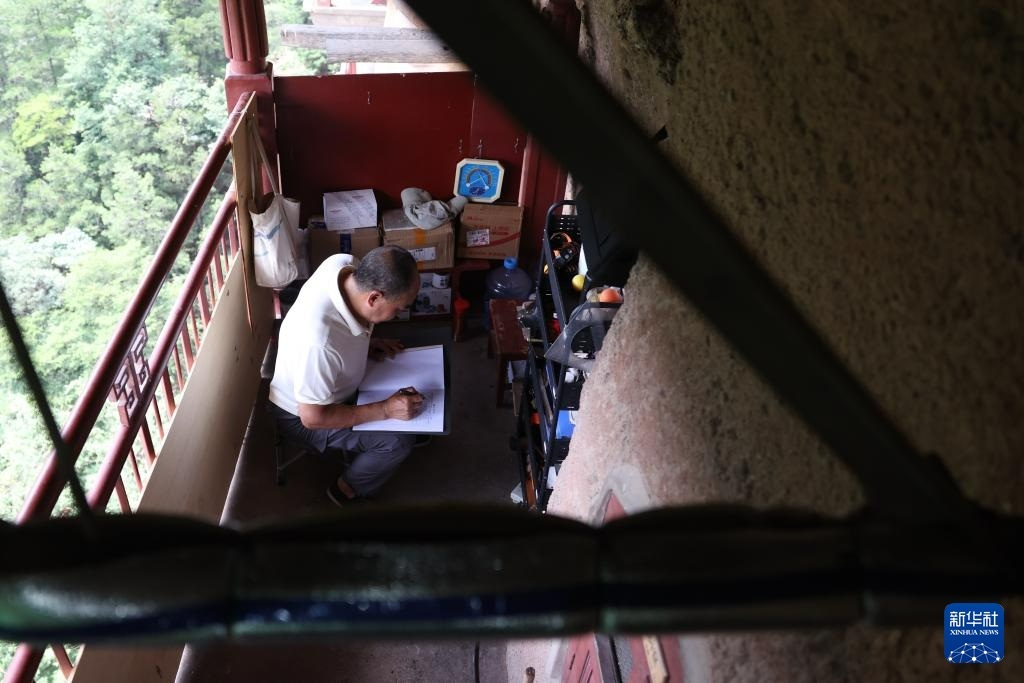 牟常有在麦积山石窟157窟前填写文物修复施工日志，为修复工作做准备（7月16日摄）。新华社记者　陈斌　摄