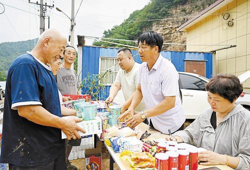 7月31日，六道沟村村干部正在向村民发放食品。本报见习记者 张 昊摄