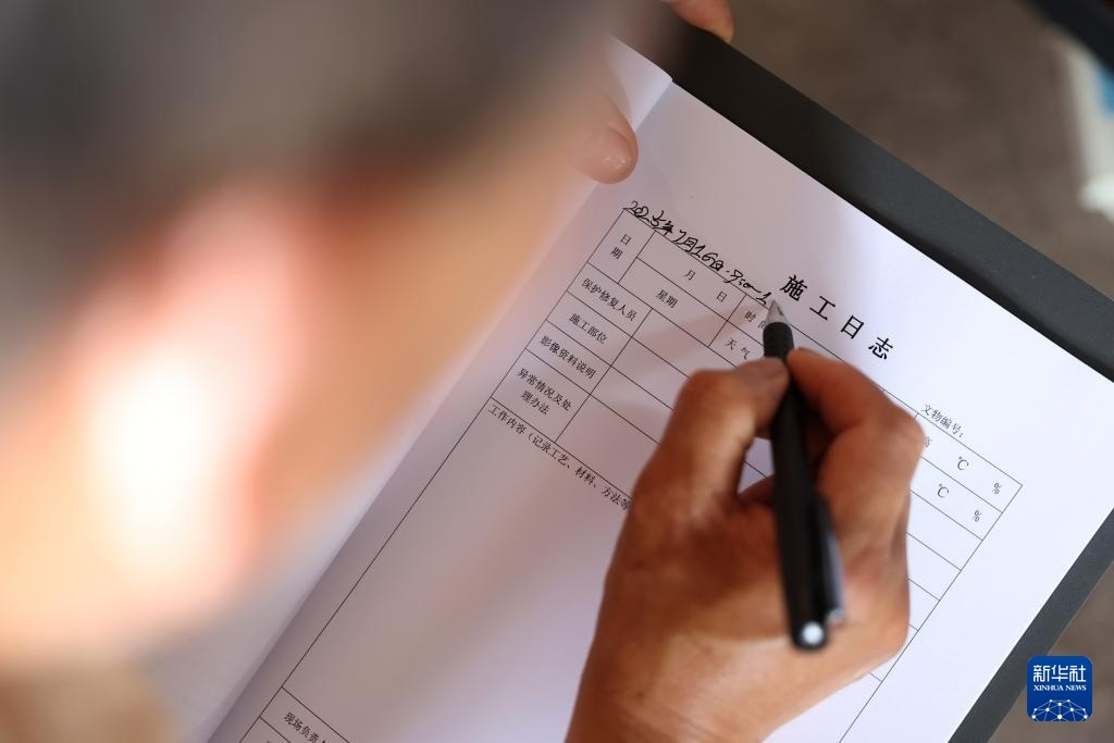 牟常有在麦积山石窟157窟前填写文物修复施工日志，为修复工作做准备（7月16日摄）。新华社记者　陈斌　摄