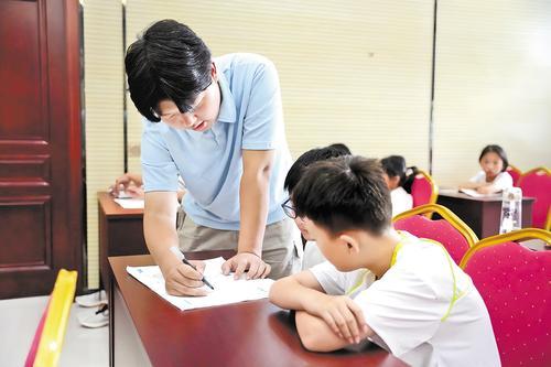 7月28日，隆尧县隆尧镇东河村村委会会议室，李道路（左）为学生讲解暑假作业。本报见习记者 闫德见摄