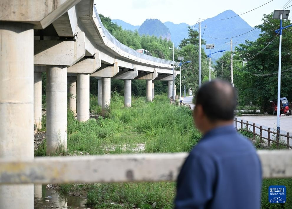 在甘肃省天水市麦积区麦积镇麦积村，牟常有站在高架桥下眺望远方的麦积山（7月16日摄）。新华社记者　蔡湘鑫　摄