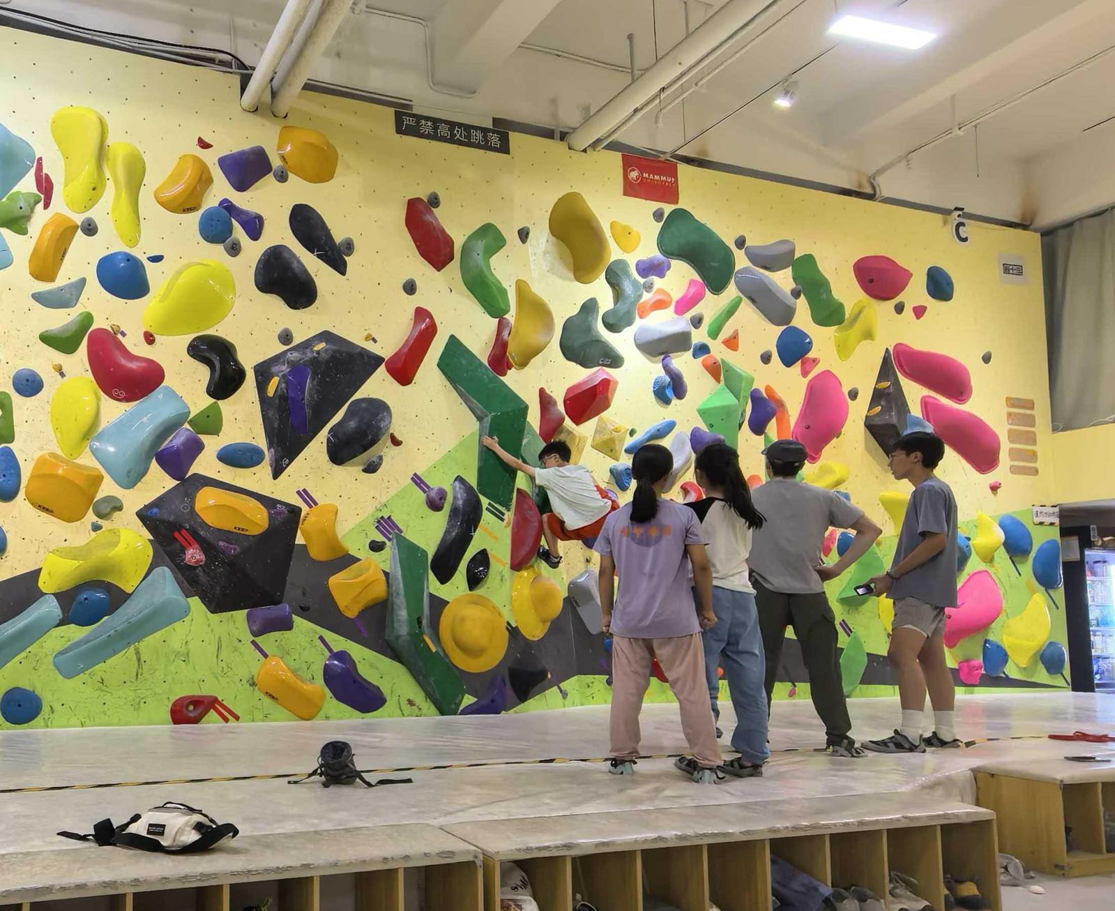 在攀岩馆内,几位顾客正讨论线路攀爬技巧。