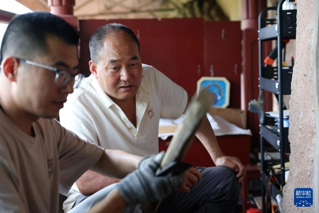 牟常有（右）在正在修复的麦积山石窟157窟前指导徒弟李浩亮搭建用于文物修复的木骨架（7月16日摄）新华社记者　陈斌　摄