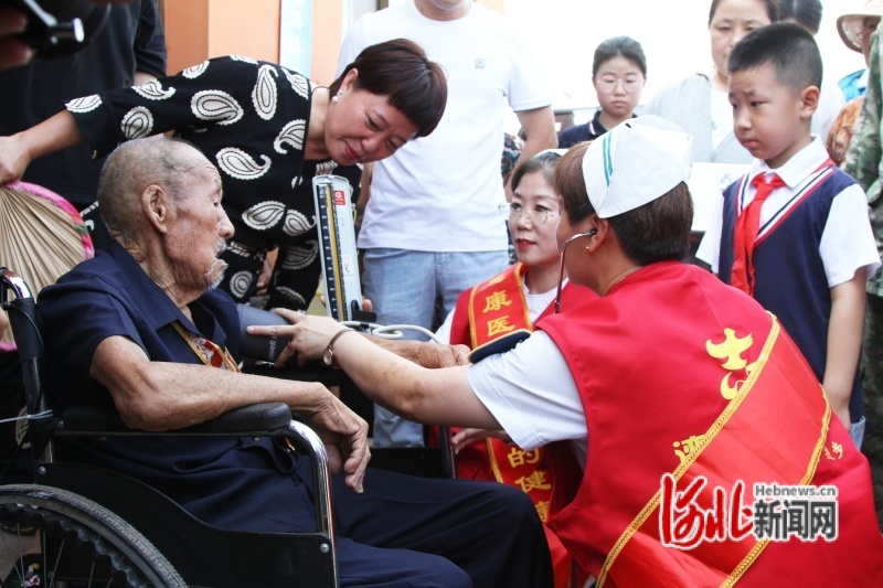 图为医疗志愿者为老兵检查身体。