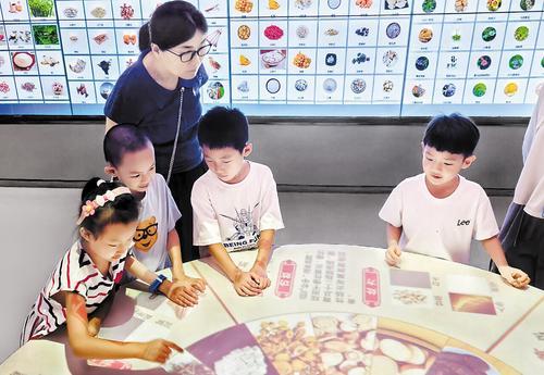 7月19日上午，乐仁堂中医药健康科普馆内，小学生们在电子装置上辨识药材。本报记者 蔡晓辉摄