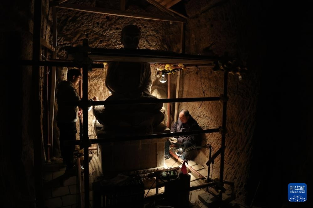 牟常有（右）和徒弟何举在麦积山石窟133窟内修复塑像（2024年11月2日摄）新华社记者　陈斌　摄