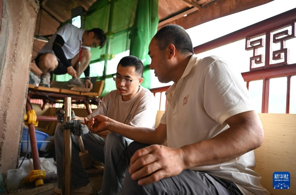 牟常有（右一）在麦积山石窟157窟前指导徒弟李浩亮制作用于塑像修复的木骨架（7月16日摄）新华社记者　蔡湘鑫　摄