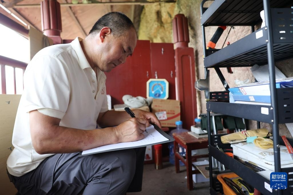 牟常有在麦积山石窟157窟前填写文物修复施工日志，为修复工作做准备（7月16日摄）。新华社记者　陈斌　摄