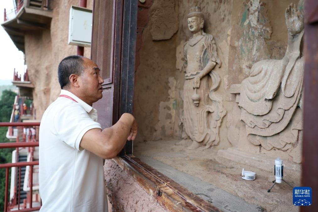 牟常有查看麦积山石窟44窟的塑像（7月16日摄）新华社记者　陈斌　摄