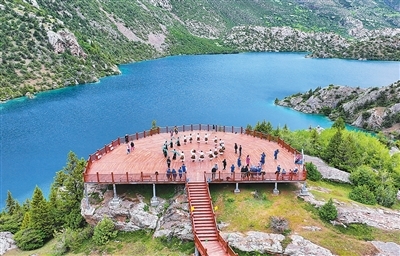 昌都市边坝县三色湖景区,普玉一村的文艺队演员为游客表演锅庄。