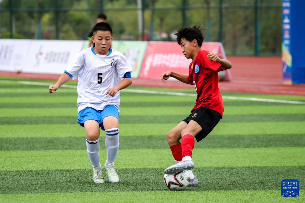 8月5日，河南省实验中学代表队球员徐梓博（右）在U13男子组比赛中扣球摆脱甘肃省古浪县代表队球员卫亮。新华社记者　郎兵兵　摄