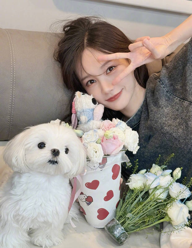 李一桐抱着花和小狗合影。