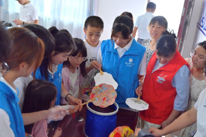 志愿服务队组织儿童开展漆扇制作活动。