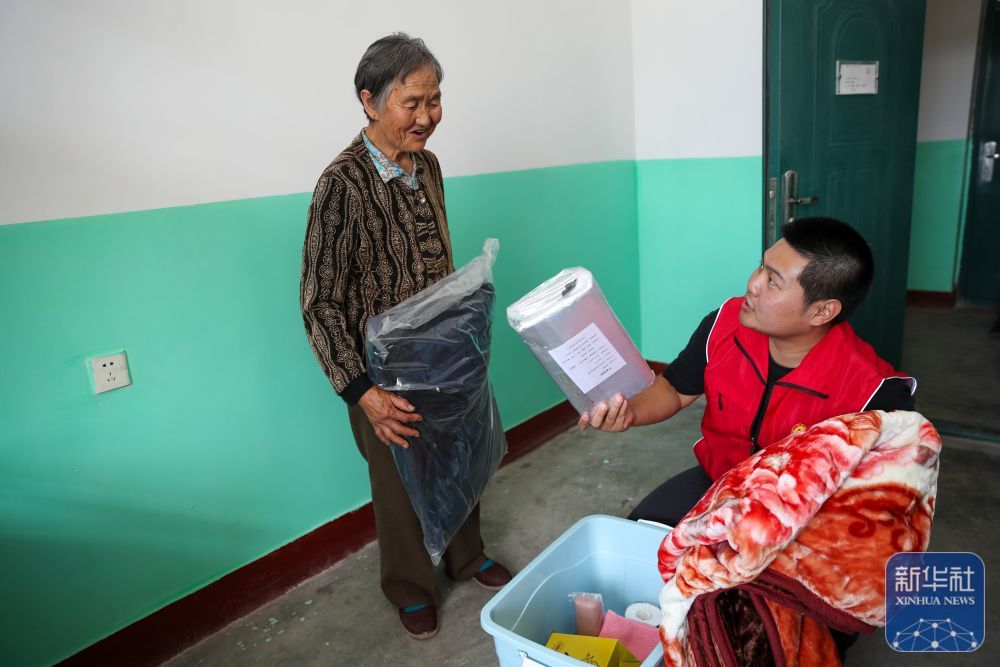 8月9日，在榆中县第三中学安置点宿舍，志愿者为受灾人员发放生活物资。