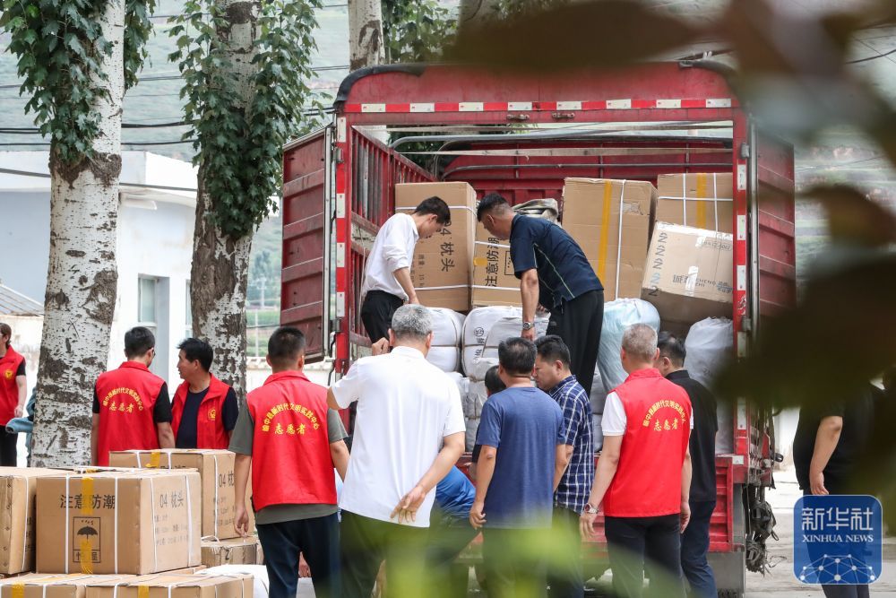 8月9日，在榆中县第三中学安置点，工作人员和志愿者搬运物资。
