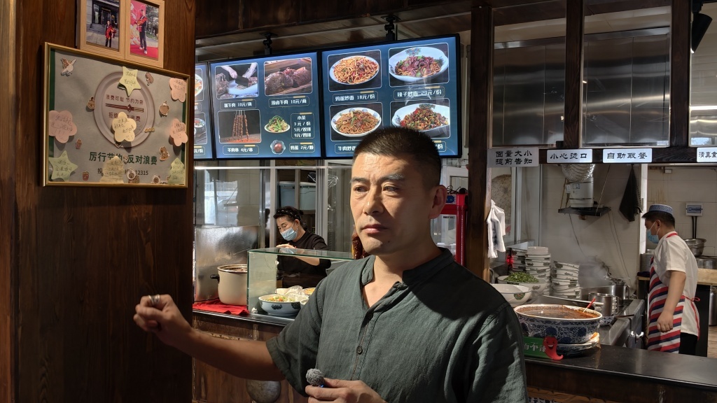 8月3日，呼和浩特古麦优品兰州牛肉面负责后勤的王高翔在介绍爱心便签板。澎湃新闻记者　王岱玉　图