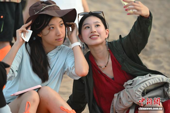 8月1日，在位于甘肃省敦煌市的鸣沙山月牙泉景区内，两岸婚生子女共同游览拍照。中新社记者 李亚龙 摄