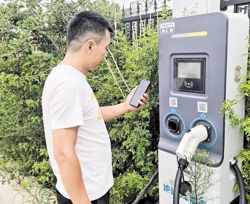 8月1日,石家庄市民康先生在河北地矿绿荫新能源汽车充电站内为车充电。本报记者 周丹平摄