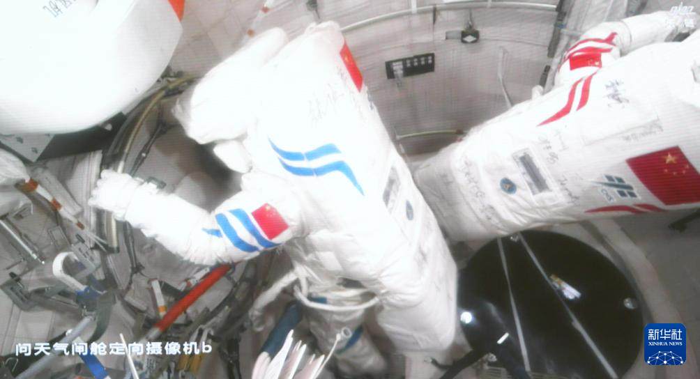 这是8月15日在北京航天飞行控制中心屏幕上拍摄的神舟二十号乘组航天员陈冬（左）与王杰准备出舱的画面。新华社记者 厉彦辰 摄