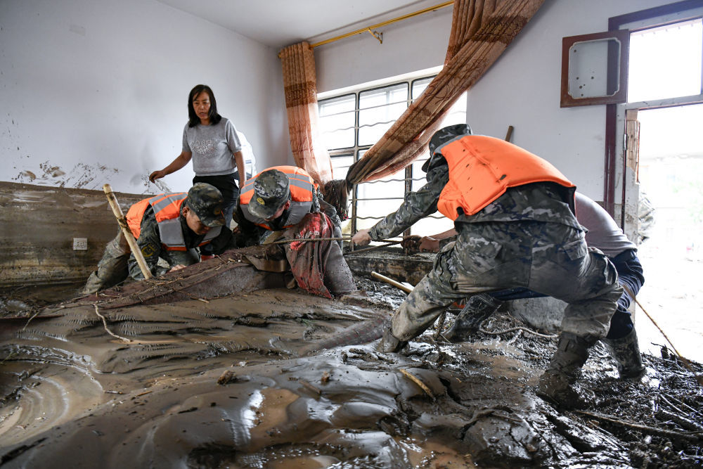 8月9日，武警甘肃总队机动支队官兵在兰州市榆中县城关镇兴隆山村受灾村民家中清理淤泥。新华社发（侯崇慧　摄）