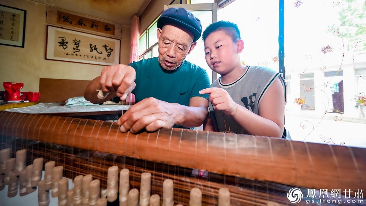 西和麻纸传承人刘智会（左）正在给曾孙传授抄纸帘技艺　李德宇　摄